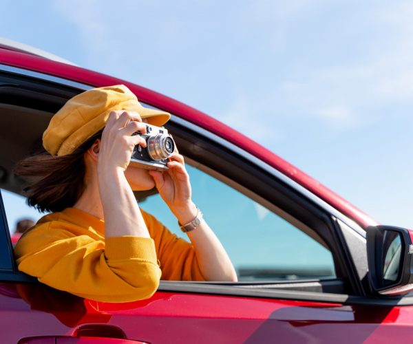 Young woman taking photos in the red car